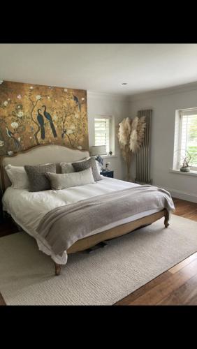 a bedroom with a large bed with a painting on the wall at Woodside in Eartham
