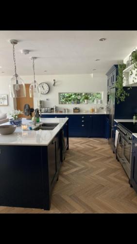 a large kitchen with blue cabinets and a white counter top at Woodside in Eartham