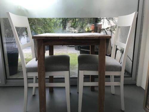 een houten tafel met 2 stoelen en een tafel met een raam bij Villa Yburg in Amsterdam