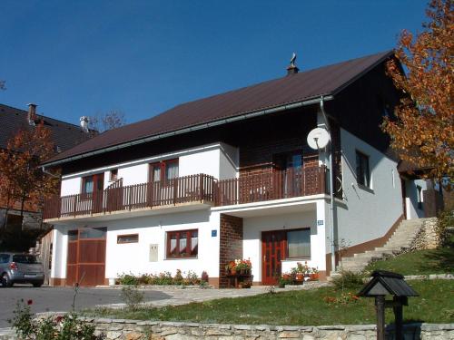 une maison blanche avec un toit noir et un balcon dans l'établissement Guest House Tone, à Poljanak