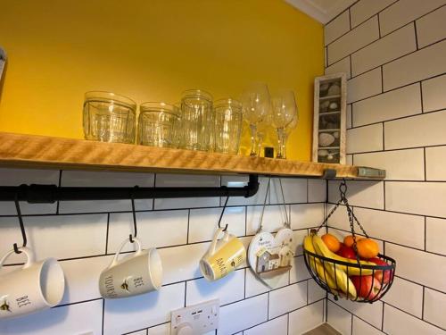 a shelf with cups and a basket of fruit at East Coast Chalets, Bee’s Knees @ California Sands in Scratby