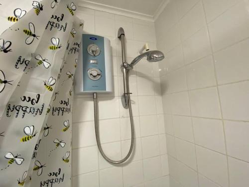 a shower in a bathroom with a shower curtain with bees at East Coast Chalets, Bee’s Knees @ California Sands in Scratby