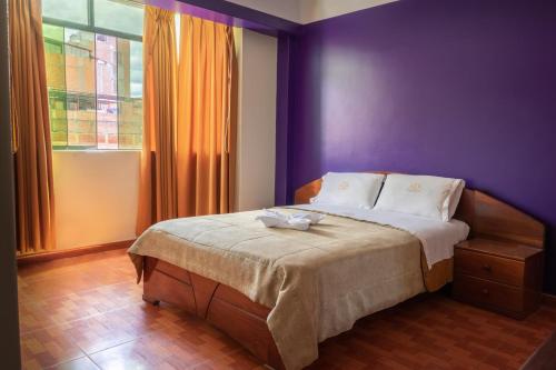 a bedroom with a bed with purple walls and a window at Hotel California in Chachapoyas
