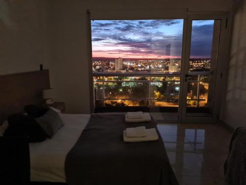 a bedroom with a bed and a window with a city view at Monoambiente CENTRICO Neuquén Capital - ESPECTACULAR VISTA in Neuquén