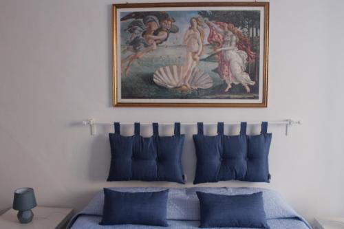 a painting above a bed with blue pillows at A casa di Martina, San Vito Chietino, Vico I della Chiesa in San Vito Chietino