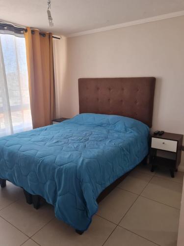 a bedroom with a bed with a blue comforter at Agradable departamento central in Calama
