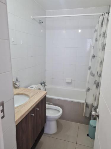 een badkamer met een wastafel, een toilet en een bad bij Agradable departamento central in Calama