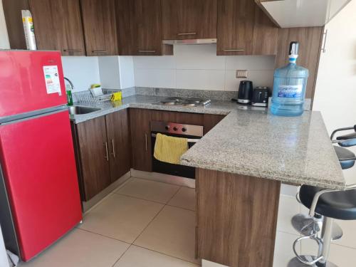una cucina con frigorifero rosso e bancone di Agradable departamento central a Calama