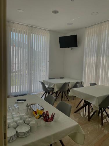 a dining room with tables and chairs and a flat screen tv at Hotel Kaligrosh in Sutomore
