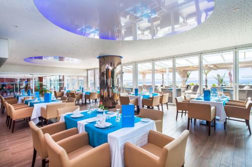 un restaurante con mesas y sillas azules y ventanas en Amadil Ocean Club en Agadir