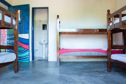 a room with two bunk beds and a bathroom at Sambaqui Hostel in Ilhabela