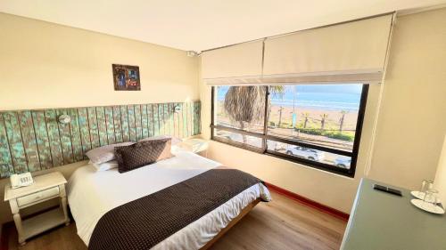a bedroom with a bed and a large window at Hotel Canto del Mar in La Serena