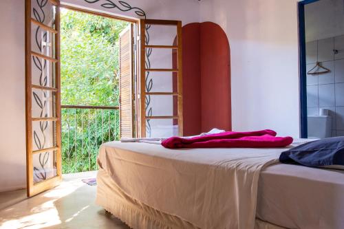 Sambaqui Hostel في إلهابيلا: غرفة نوم بسرير ومرآة ونافذة