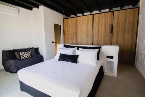 una camera con un grande letto bianco e un divano di Blue Eye Grand Villa Mykonos a Kalafatis