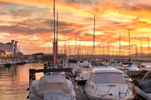 un gruppo di imbarcazioni ormeggiate in un porto turistico al tramonto di Apartamento Temático Cantabria a Camargo