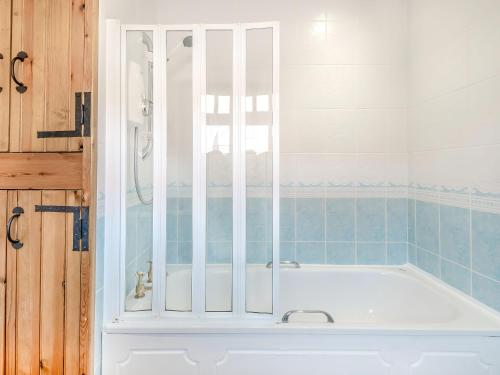 y baño con bañera blanca y azulejos azules. en Bluebell Cottage - Uk36669, en Goulsby