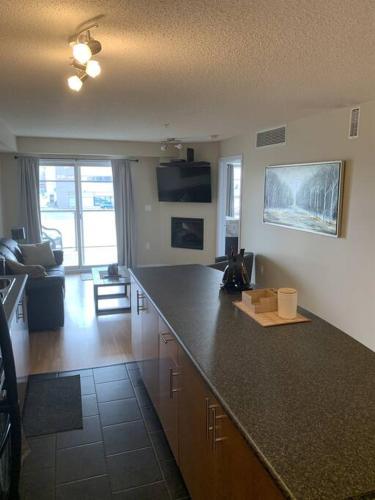 a kitchen with a counter top and a living room at Chris's Cozy Condo Times Square Rogers Place Edmonton in Edmonton