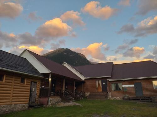 a log cabin with a mountain in the background at Altyn Arashan guesthouse in Mineralʼnyy Istochnik Altyn-Arasan