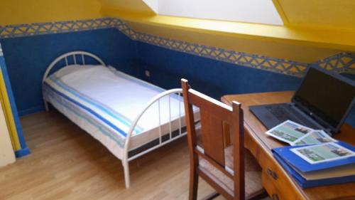 een kleine kamer met een bed en een bureau met een laptop bij La Bourgandie in Englesqueville-la-Percée