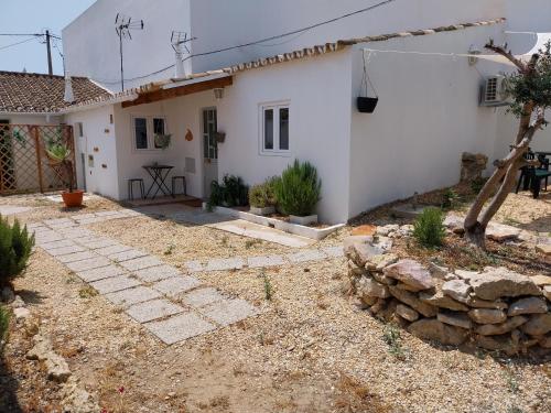 a white house with a stone wall and a yard at Casa Algarvia G&S in Luz de Tavira