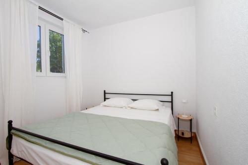 a white bedroom with a bed and a window at Sole e Limone in Kraj