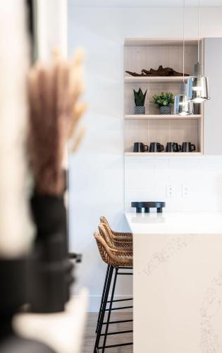 a kitchen with a white counter and two stools at Prime Revy Penthouse in Revelstoke
