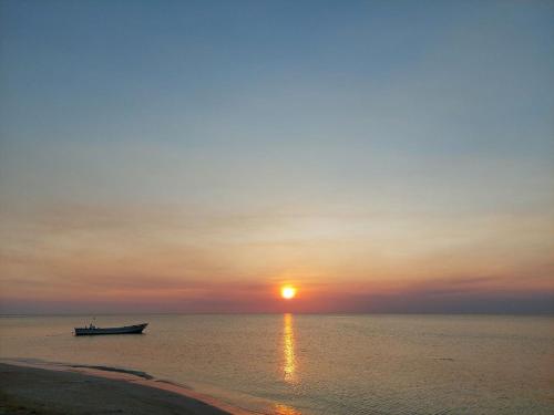 a boat in the ocean with the sun setting at Sunset Bay B&B in Corn Island