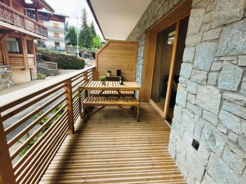 une terrasse en bois avec des bancs et un mur en pierre dans l'établissement Appartement neuf au centre des Gets avec balcon, sauna, parking et proximité pistes - FR-1-598-138, aux Gets