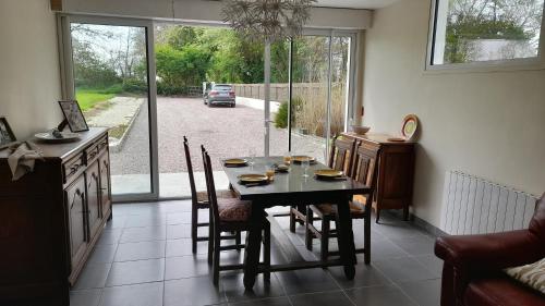 een eetkamer met een tafel en stoelen en een raam bij La Bourgandie in Englesqueville-la-Percée