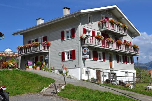 un bâtiment blanc avec des boîtes de fleurs sur les balcons dans l'établissement Gasthaus Alpina, à Tschappina