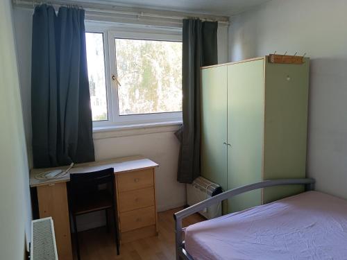 um quarto com uma cama, uma secretária e uma janela em Guest House Private Room near Glasgow City Centre St George's Rd em Glasgow