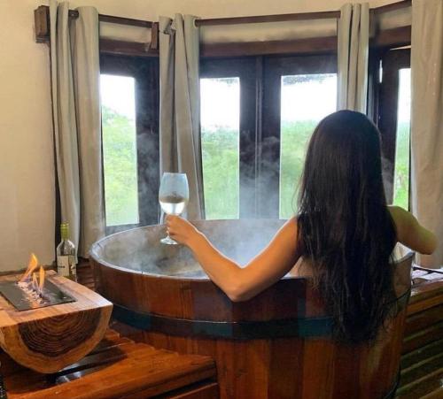 坎巴拉的住宿－Rodeio das Lagoas，浴缸里拿着一杯葡萄酒的女人