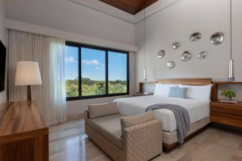 a bedroom with a bed and a chair and a window at Fairmont Heritage Place Mayakoba in Playa del Carmen