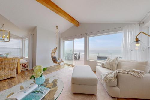 a living room with a white couch and a large window at Salty Shore in Rockaway Beach