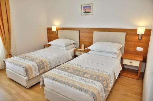 a hotel room with two beds and two tables at Hotel Leonardo in Međugorje