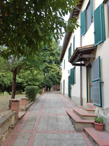 una strada di ciottoli tra due edifici con persiane verdi di Agriturismo Le grondaie a Siena
