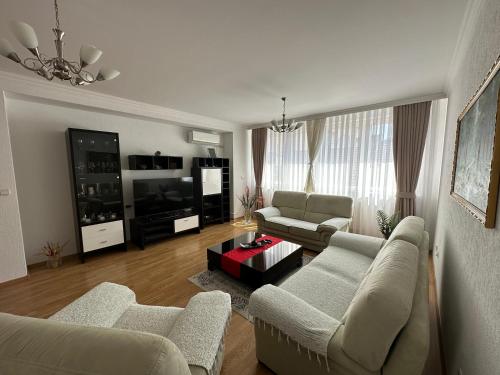 ein Wohnzimmer mit 2 Sofas und einem TV in der Unterkunft Spacious 3-bedroom Condo Next to City Center in Pristina