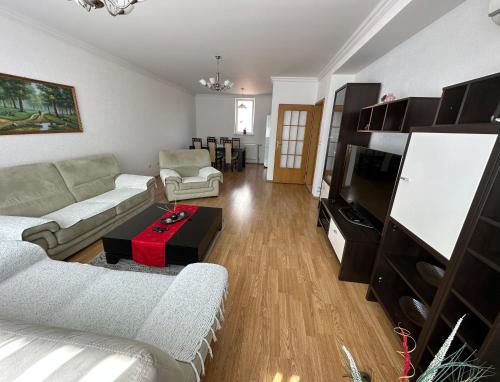 ein Wohnzimmer mit einem Sofa und einem TV in der Unterkunft Spacious 3-bedroom Condo Next to City Center in Pristina