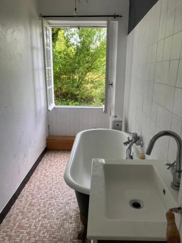 une salle de bain blanche avec un lavabo et une fenêtre dans l'établissement LA GRANGE DU CHAPELAT, à Bourdeilles