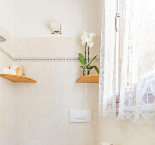 uma casa de banho com prateleiras e um vaso de flores na parede em Residence Rialto em Milano Marittima