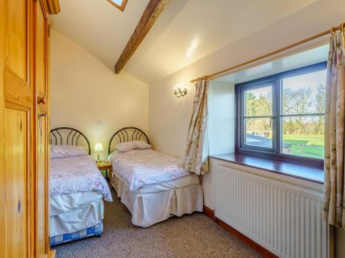 dwa łóżka w pokoju z oknem w obiekcie The Shippon w mieście Poulton le Fylde