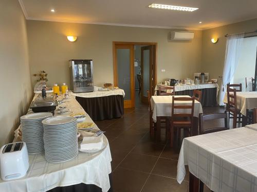 Villa Da Madalena في مادالينا: غرفة طعام مع طاولات وأطباق بيضاء على الطاولة