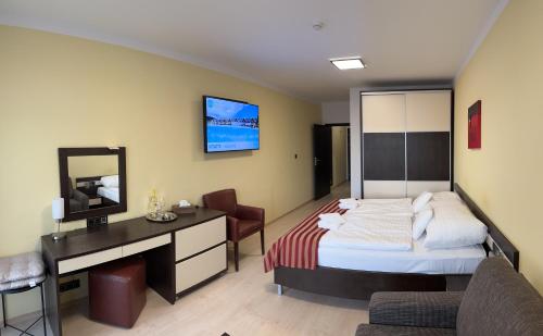 a bedroom with a bed and a desk and a television at Apartmán Bešeňová 289 in Bešeňová