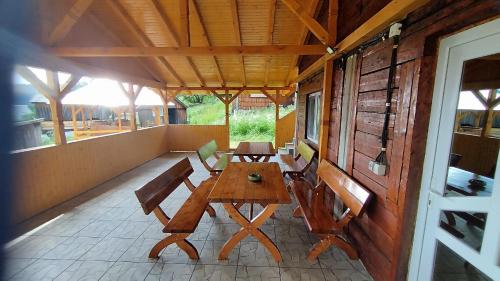 a porch with a wooden table and chairs on it at Cabana Trif in Horea