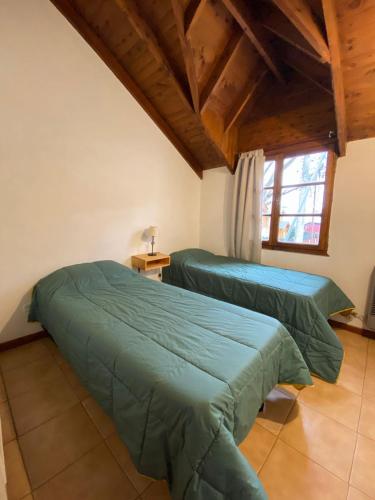 2 camas verdes en una habitación con ventana en Alice alojamiento en San Martín de los Andes