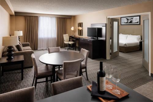 Una habitación de hotel con una cama y una mesa con una botella de vino en Pomeroy Hotel & Conference Centre, en Grande Prairie