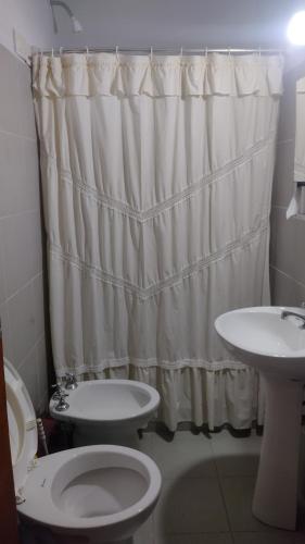 y baño con cortina de ducha, aseo y lavamanos. en Monoambiente céntrico en Concordia