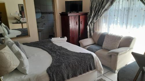 een slaapkamer met een bed, een stoel en een spiegel bij Umqhele BnB in Richards Bay