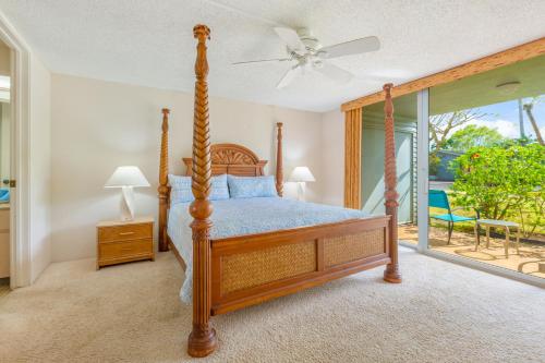 1 dormitorio con cama con dosel y balcón en Beautiful Princeville Garden Condo with lots of Amenities C2108 en Princeville