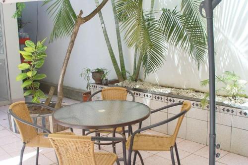 a glass table and chairs on a patio with palm trees at Happy Day Pucallpa in Pucallpa